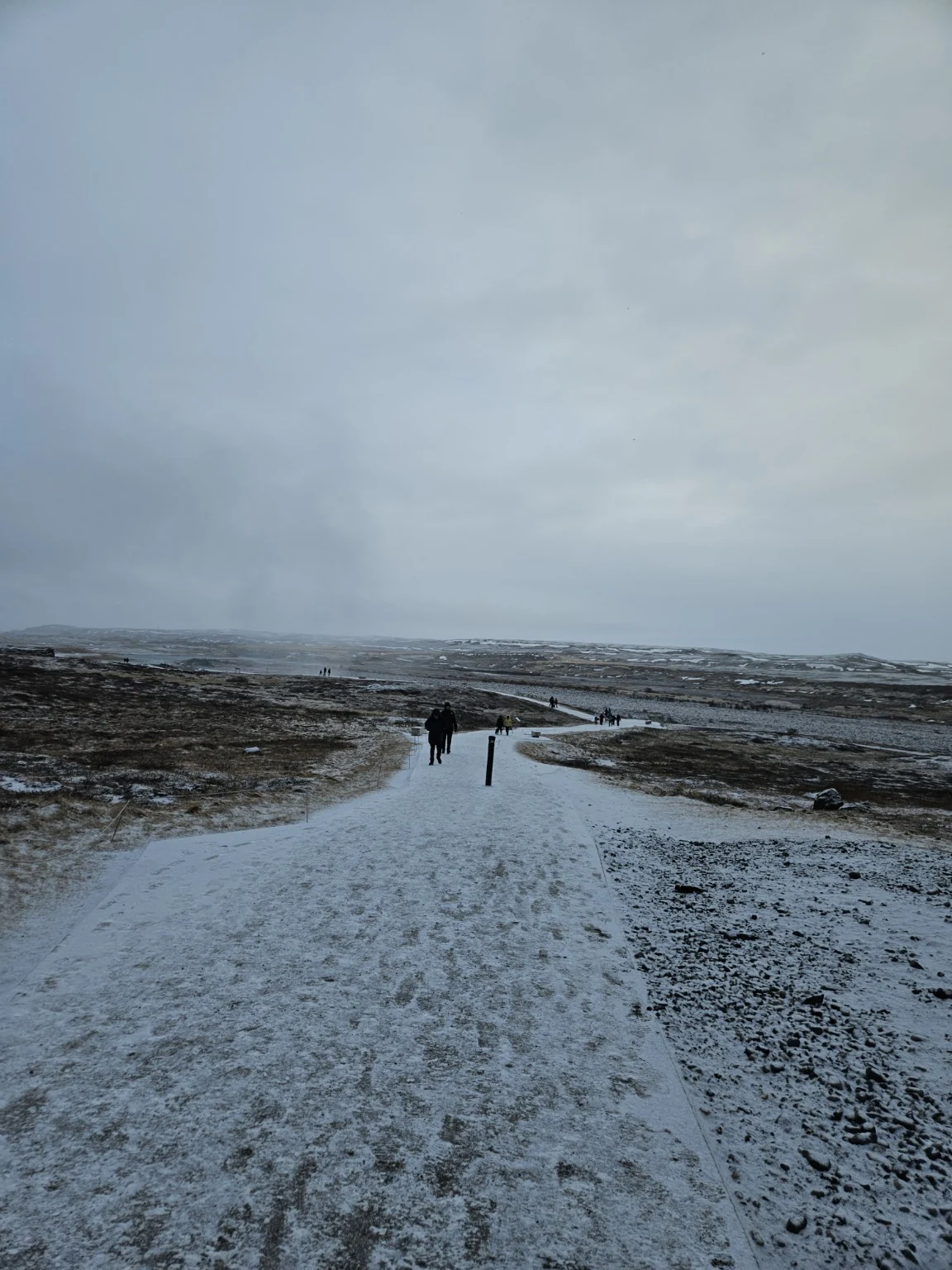 A broad snowy walking path leading from the parking area toward the Gullfoss viewpoints