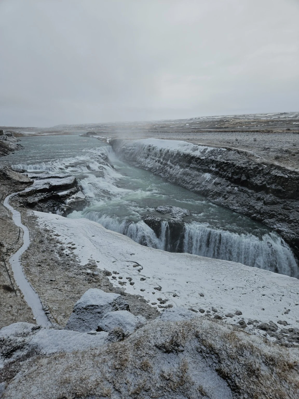 The broad upper cascade of Gullfoss flowing through a snow-covered winter landscape