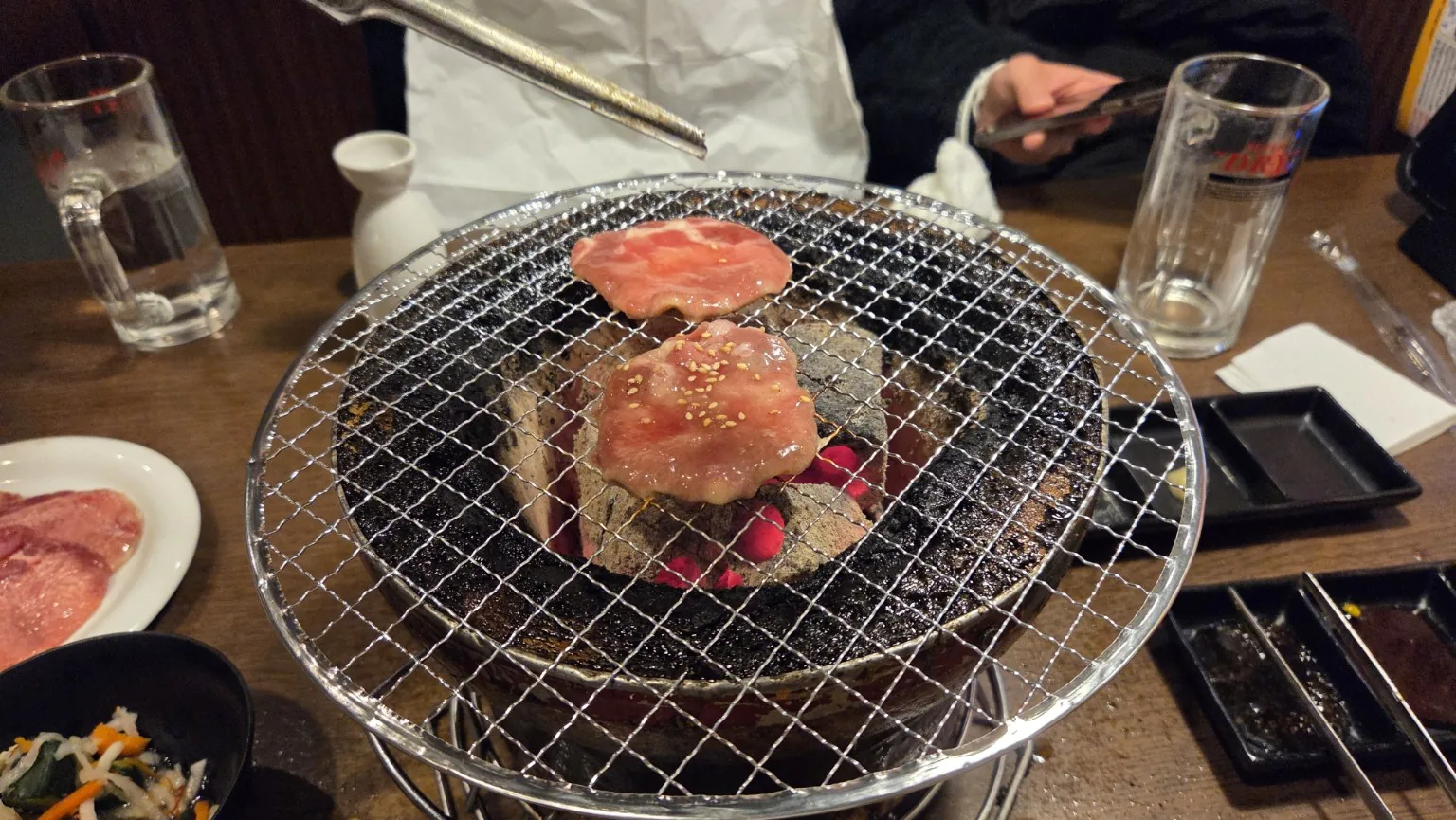 Yakiniku cooking over a charcoal grill at Gyushige Fujikyu Highland Mae