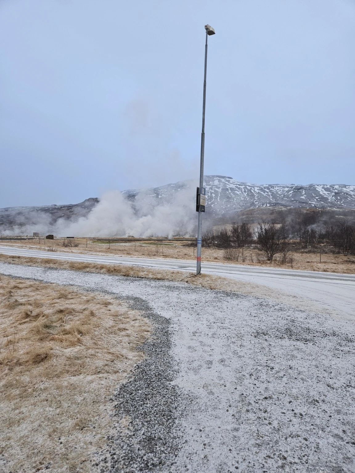 Geothermal steam rising across the road near Hótel Geysir