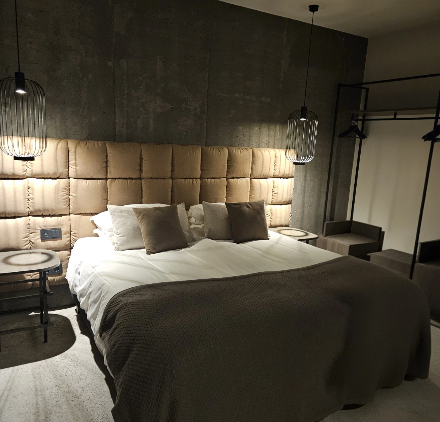 A clean Hótel Geysir room with a concrete wall, warm padded headboard and neatly made bed