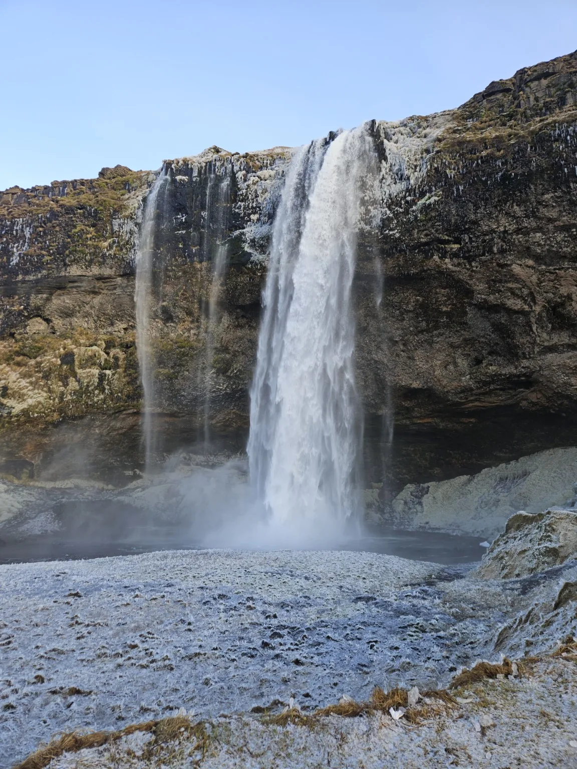 Seljalandsfoss rising above a winter landscape edged with ice and frost