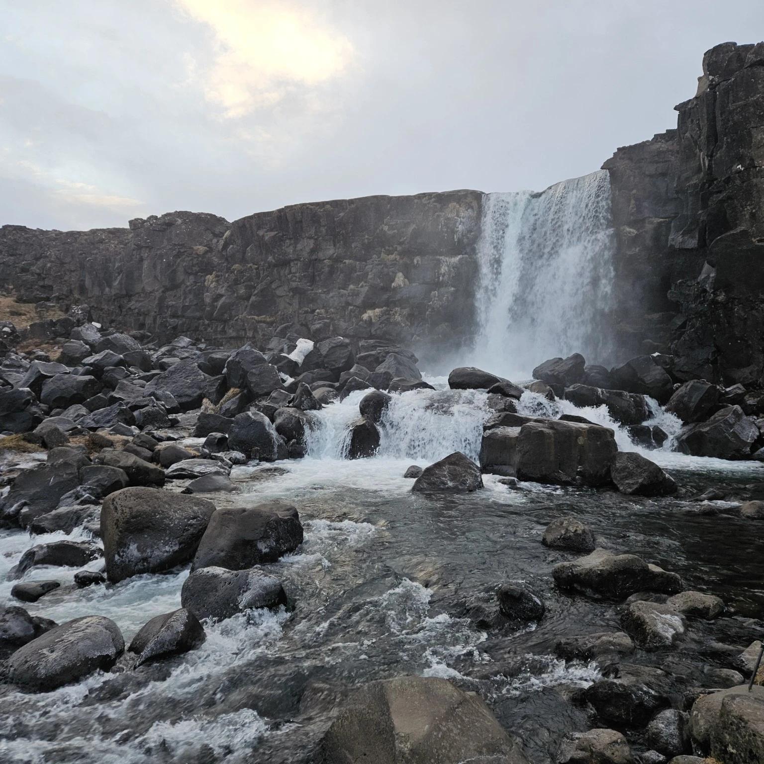 Öxarárfoss dropping from a dark rock cliff at Þingvellir